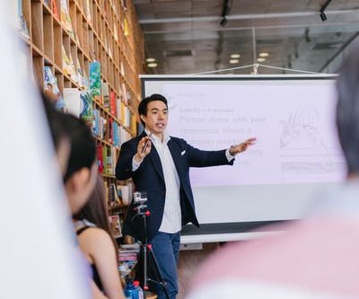 Man In Suit Jacket Standing Beside Projector Screen