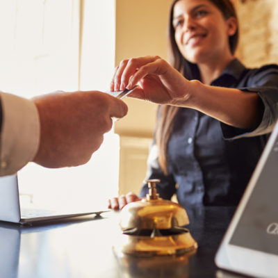 Guest Takes Room Key Card at Check in Desk of Hotel Close Up the places youll go 7 terrific no hotel travel accommodations
