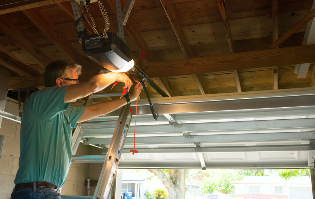 Professional Automatic Garage Door Opener Repair Service Technician Man Working on a Ladder at a Home Residential Location Making Adjustments and Fixing It While Installing It 5 warning signs you may have a broken garage door