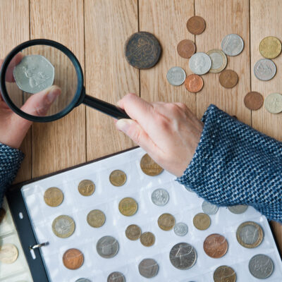 Woman numismatist Views Coins from a Coin Album Through a Magnifying Glass Top View 5 tips for collecting custom coins
