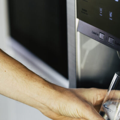 Male Hand is Pouring Cold Water and Ice Cubes from Dispenser of Home Fridge how to choose a frigidaire refrigerator water filter a guide