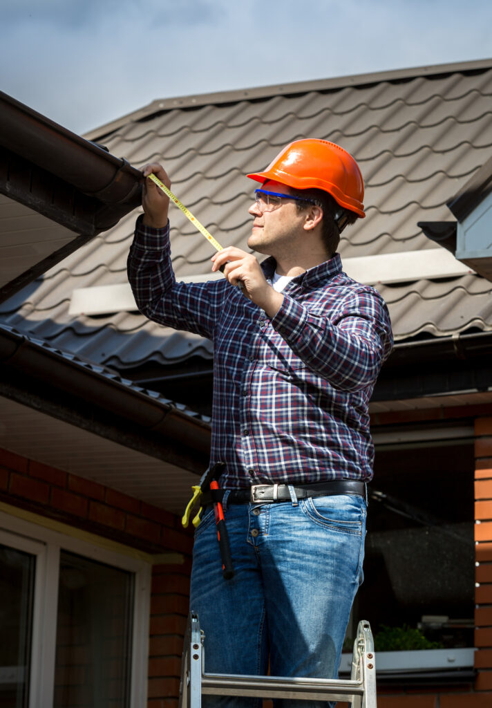 Handyman Standing on High Ladder and Measuring Roof with Tape 4 signs you need a roof inspection