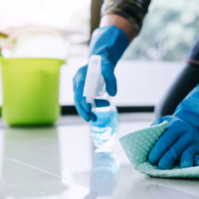 Husband Housekeeping and Cleaning Concept Happy Young Man in Blue Rubber Gloves Wiping Dust Using a Spray and a Duster While Cleaning on Floor at Home 4 key questions to ask before hiring a house cleaner