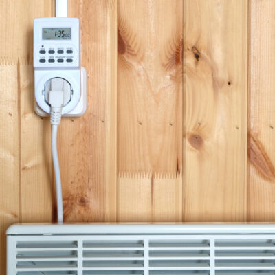 Working White Electric Convector Heater Plugged to Timer Power Socket Operated in Smart House System Against Wooden Wall Inside Room Front View Closeup what are the main types of home heating systems